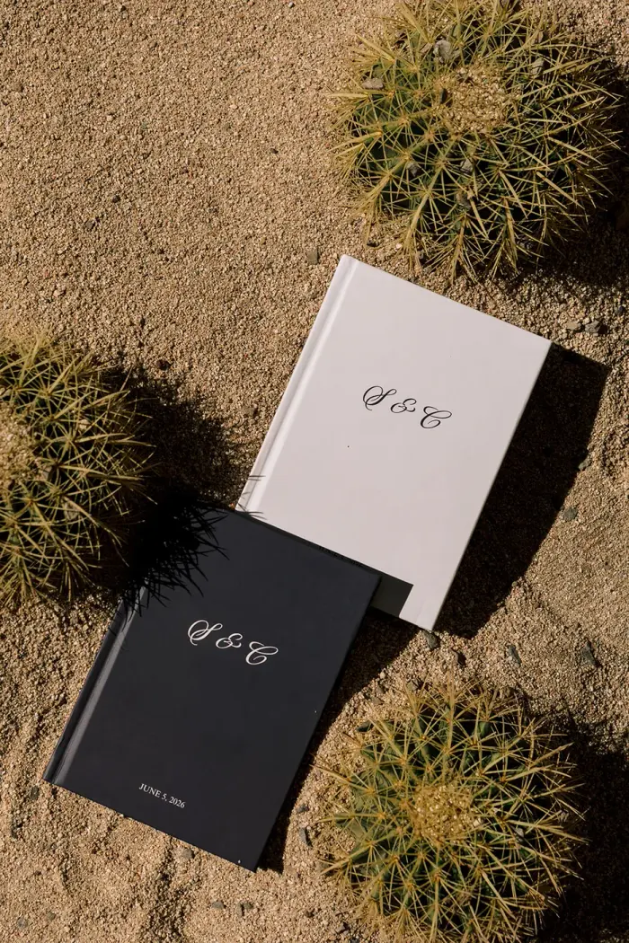 The monogrammed wedding albums resting on the sand