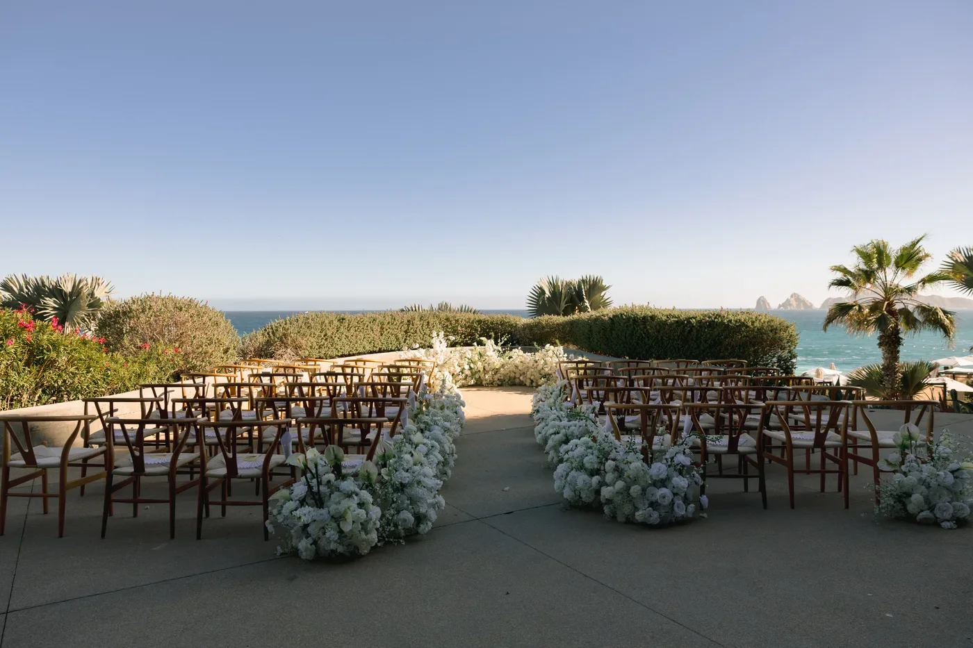Ceremony chairs and white florals with El Arco on the horizon