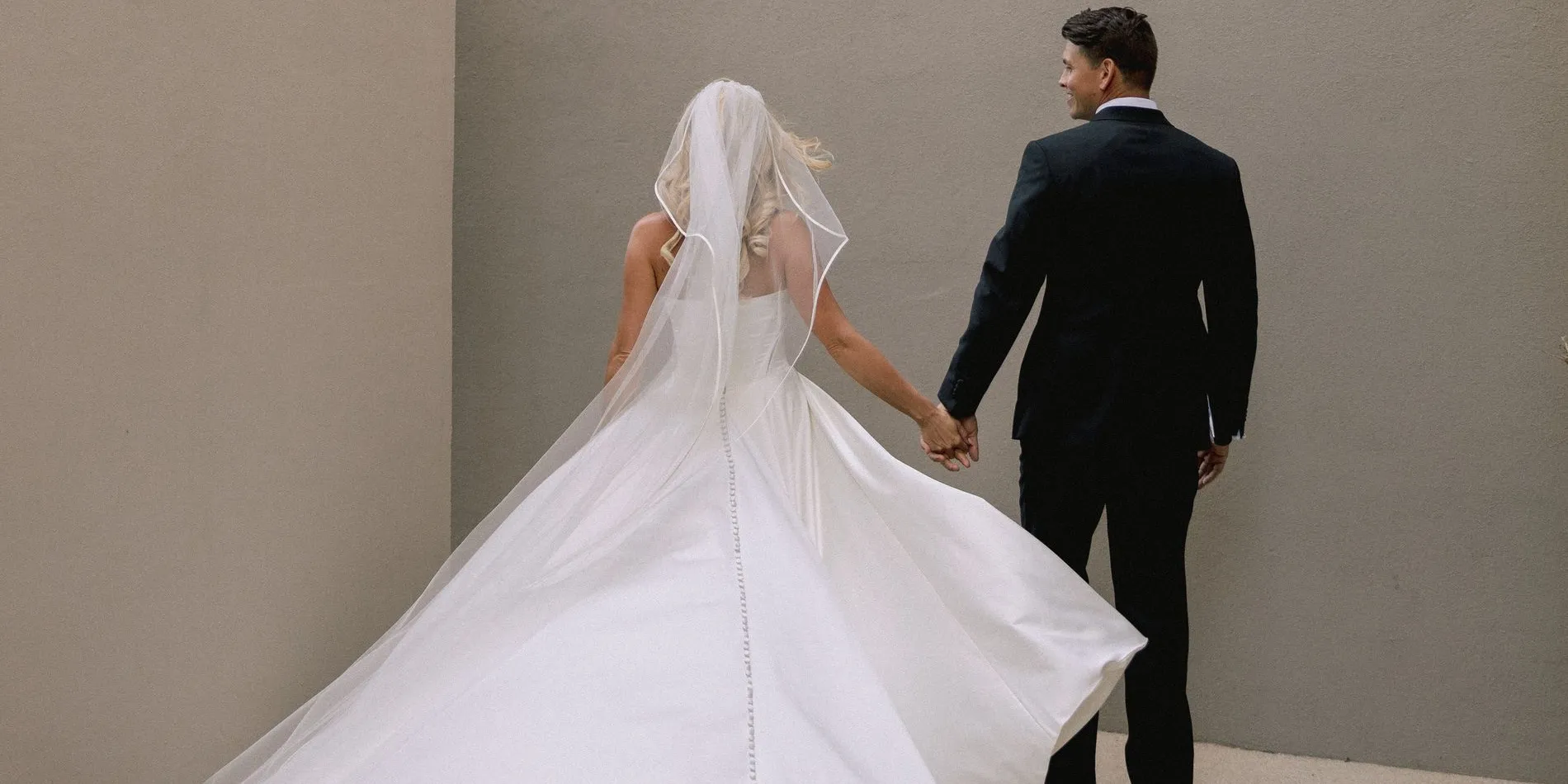 A bride in a veil, turned away, her train sweeping behind her